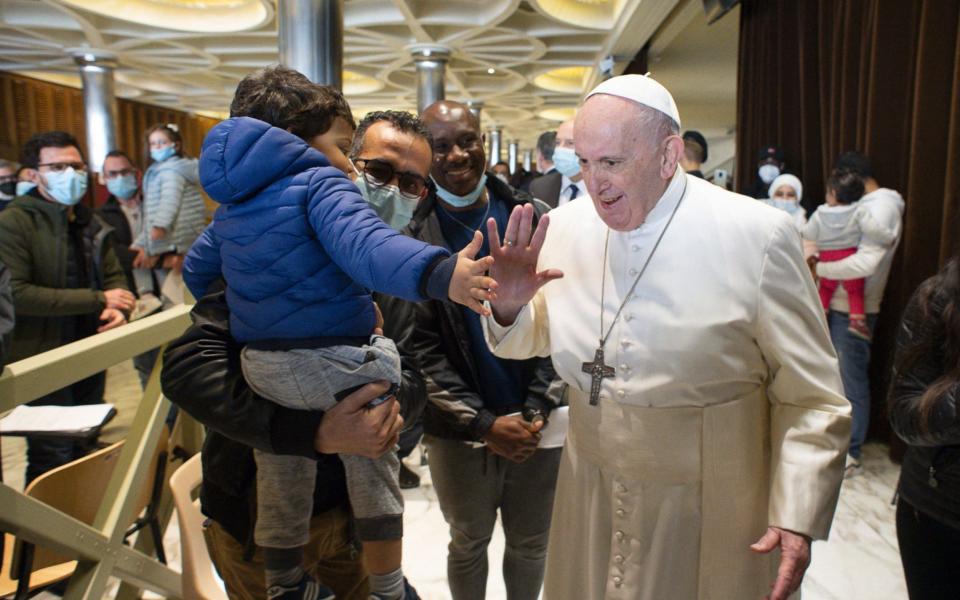 Pope Francis tap hands with a child during his visit to a vaccination centre on Friday - AFP