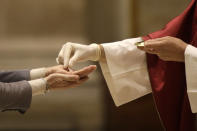 Father Jose Maria Galvan, wearing gloves to prevent the spread of COVID-19, places the host in the hands of a parishioner during the morning mass at St. Eugenio Church, in Rome, Monday, May 18, 2020. Italy partially lifted lockdown restrictions Monday after a two-month coronavirus lockdown. (AP Photo/Alessandra Tarantino)