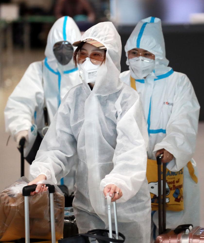 Passengers in protective clothing arrive at Incheon airport, South Korea.