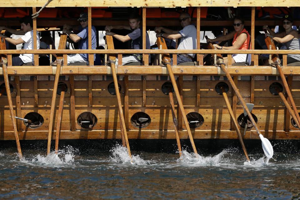 In this Sunday, Sept. 16, 2018 photo, visitors row the Olympias, replica of an ancient galley, at Saronic gulf in southern Athens. The 37-meter (121-foot) wooden vessel moored off southern Athens is an experimental reconstruction of the trireme, the sleek ancient Greek warship that halted a Persian invasion of Europe and ruled the Mediterranean for centuries. Every summer, visitors can get a whiff of life in the galleys 2,500 years ago by joining the crew of the Olympias, and work up a sweat rowing it. (AP Photo/Thanassis Stavrakis)