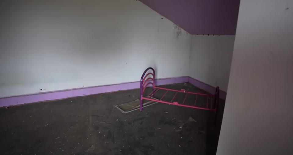A pink bed frame in a rundown room