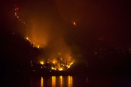 The Chelan Complex Fire in Chelan, Washington is reflected on Lake Chelan as pictured at night from Manson, Washington, August 22, 2015. REUTERS/Jason Redmond