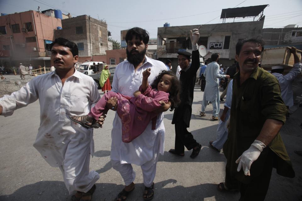 A volunteer carries a girl, who was injured in a bomb blast as she arrives at a hospital in Peshawar September 29, 2013. Twin blasts in the northwestern Pakistan city of Peshawar killed 33 people and wounded 70 on Sunday, a week after two bombings at a church in the frontier city killed scores, police and hospital authorities said.REUTERS/ Fayaz Aziz (PAKISTAN - Tags: POLITICS CIVIL UNREST CRIME LAW)