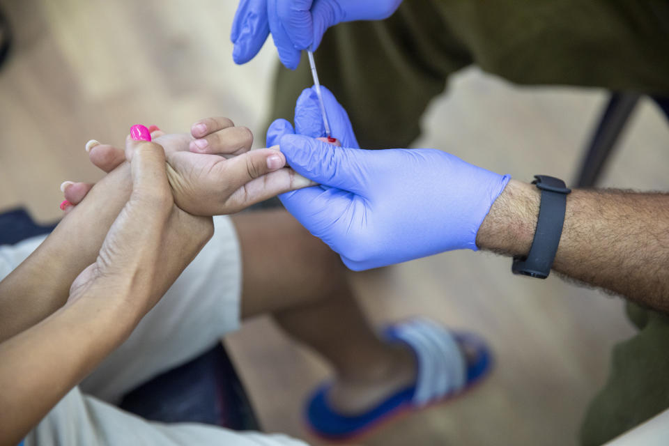 An Israeli soldier conducts a COVID-19 antibody test on a child in Hadera, Israel, Monday, Aug. 23, 2021. Ahead of the opening of the school year on Sept. 1, the Israeli army's Home Front Command is conducting serology tests on children age 3-12 who have not yet tested positive for coronavirus and are not yet listed as recovered, to see if they have antibodies. (AP Photo/Ariel Schalit)