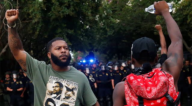 Demonstrators raise their hands in the air as law officials march down a street during protests in Baton Rouge. Photo: Reuters/Shannon Stapleton