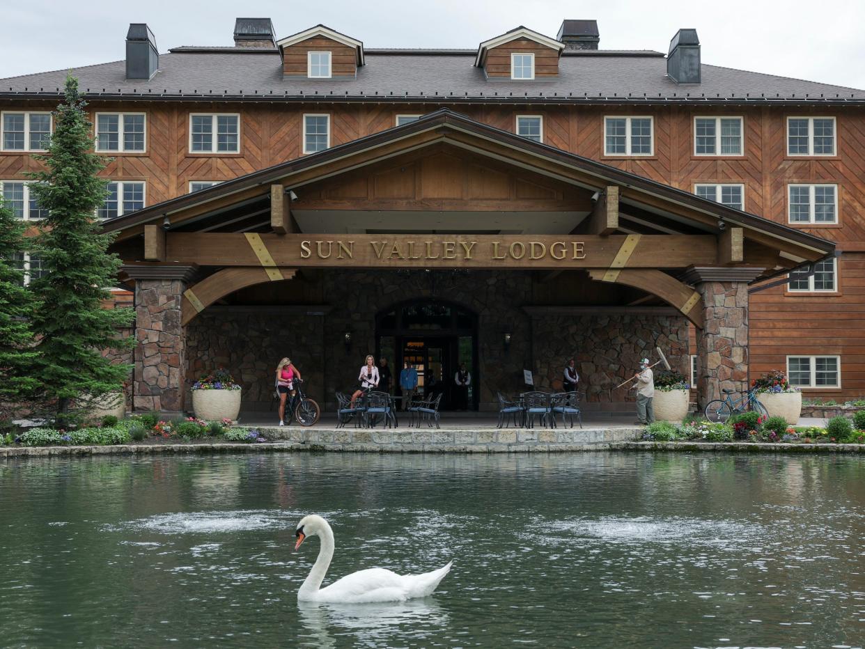 People stand outside the Sun Valley Lodge entrance where swans swim in pond