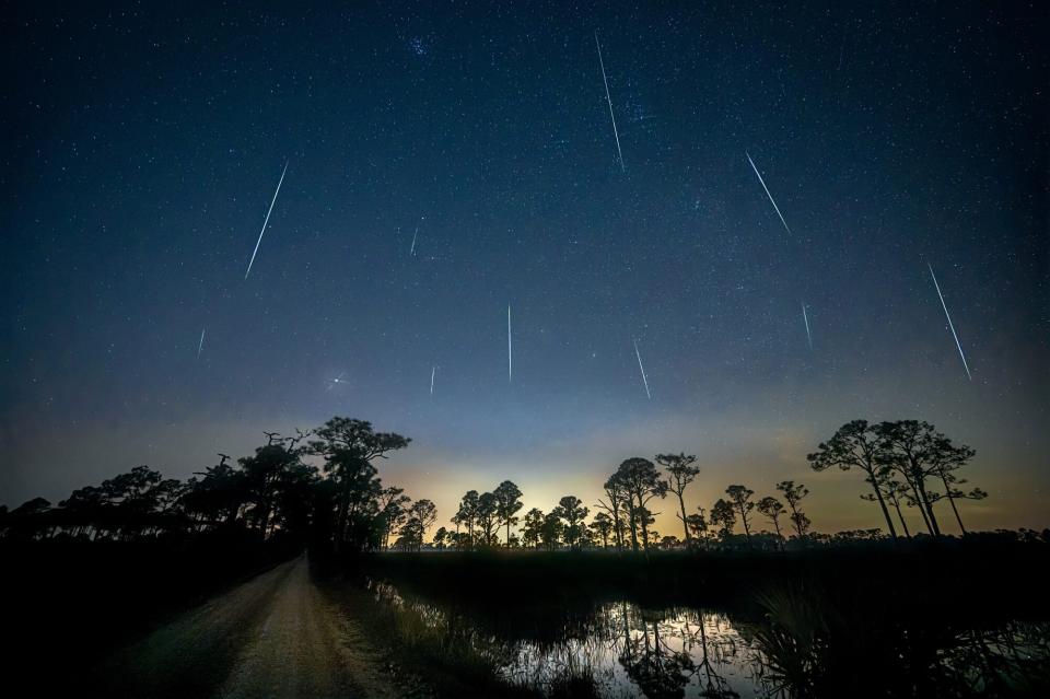 Geminid Meteor Shower 2020 over pond and direct road in Fred C. Babcock/Cecil M. Webb Wildlife Management Area near Punta Gorda, Florida. The Geminids meteor shower is caused by the object 3200 Phaethon which is thought to be a Palladian asteroid with a "rock comet" orbit. Geminids were first observed in 1862.