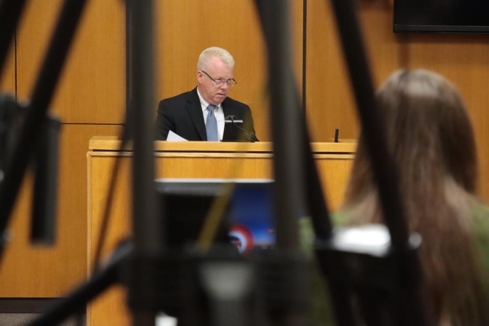 Devin Newell, a senior technical expert with General Motors, is pictured through the legs of a TV camera tripod while testifying Thursday, May 2, 2024, in Lenawee County District Court during the preliminary examination of murder and evidence tampering charges against Dale Warner in the disappearance of his wife, Dee. Newell testified about the use of the OnStar app connected with Dee's Cadillac Escalade.