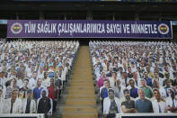 A view of cardboards with photographs of medical staff on the stands prior to a Turkish Super League soccer match between Fenerbahce and Kayserispor in Istanbul, Friday, June 12, 2020. The banner reads in Turkish: 'To all our medical staff with respect and gratefulness'. The Turkish Super Lig resumed its season on Friday without spectators after it had suspended games since March 20 due to the coronavirus pandemic, later than many other European leagues. (Erdem Sahin/Pool via AP)