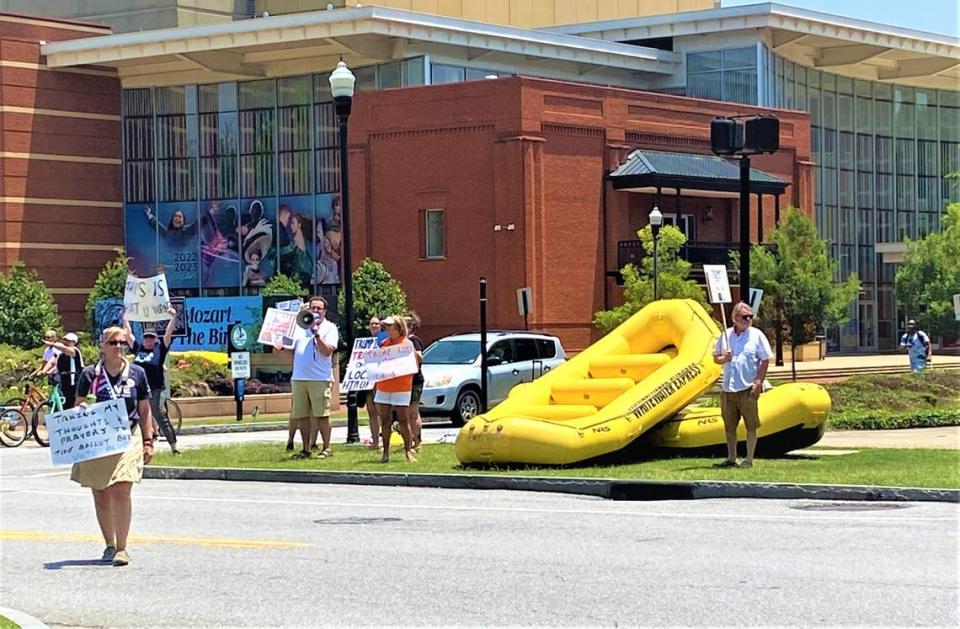 About 10 protesters stand in the median at Broadway and 10th Street in downtown Columbus on June 10, 2023, to demonstrate against former president Donald Trump, who spoke later in the afternoon at the Columbus Convention & Trade Center during the Georgia Republican Party’s State Convention. Tim Chitwood/tchitwood@ledger-enquirer.com