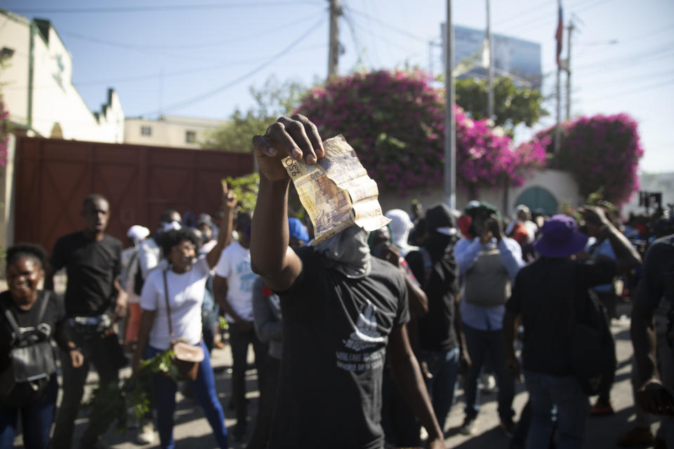 A factory worker holds up banknotes totaling 500 gourdes ($5) during a protest demanding a salary increase, in Port-au-Prince, Haiti, Thursday, Feb. 10, 2022. The workers employed at factories that produce textiles and other goods say they make 500 gourdes a day for nine hours of work and are seeking a minimum of 1,500 gourdes ($15) a day. (AP Photo/Odelyn Joseph)