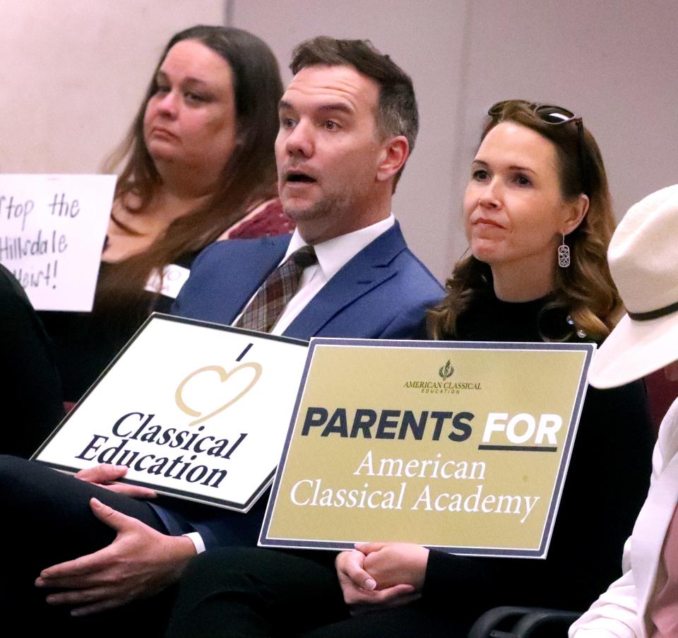 Supporters of the American Classical Academy Joel Schellhammer, left, and Michelle Garcia, right, react to a Rutherford County Board of Education vote to accept the public charter school plan Tuesday, April 25, 2023. In the background far left, Oceana Glantz holds a sign in opposition for a charter school that will use free curriculum and teacher training from the conservative, Christian Hillsdale (Michigan) College.