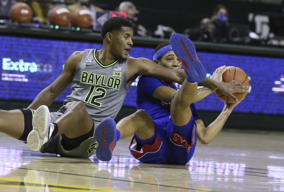 Baylor guard Jared Butler, left, battles Kansas guard Dajuan Harris for a loose ball in the first half of an NCAA college basketball game, Monday, Jan. 18, 2021, in Waco, Texas. (Rod Aydelotte/Waco Tribune-Herald via AP)