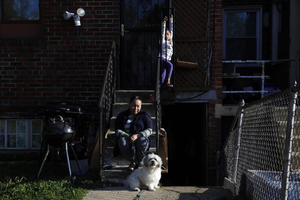 Allison, 5, plays, as her mother Janeth sits outside their basement apartment unit with the family dog, Henry, Wednesday, April 15, 2020, in Washington. Since this image was taken Janeth and her husband Roberto have been diagnosed with COVID-19. (AP Photo/Jacquelyn Martin)