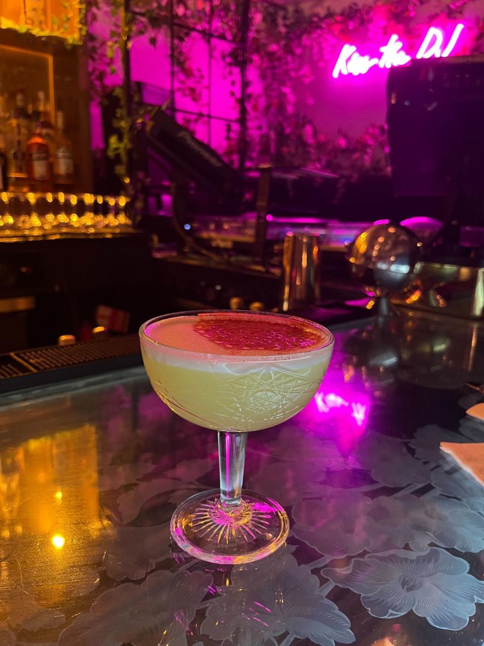 a glass of pink liquid on a bar