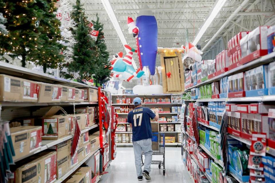 A shopper is seen walking through an aisle of Christmas trees and lights displayed for sale at a Walmart.