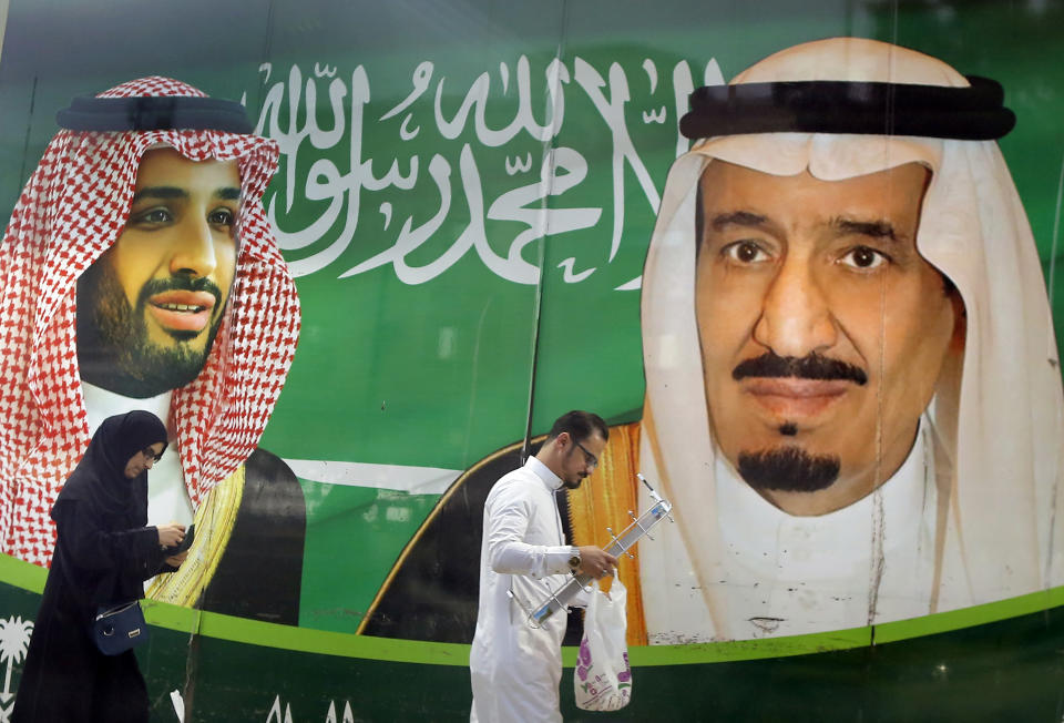 FILE - People walk past a banner showing Saudi King Salman, right, and his Crown Prince Mohammed bin Salman, outside a mall in Jiddah, Saudi Arabia, Saturday, March 7, 2020. A spike in global energy prices caused by Russia's war on Ukraine benefits Saudi Arabia as the world's top oil exporter, but problems remain for the kingdom's impulsive crown prince. (AP Photo/Amr Nabil, File)