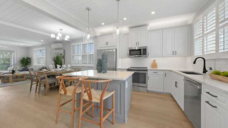 The kitchen island inside a Hunters Point home with white cabinets and wooden chairs