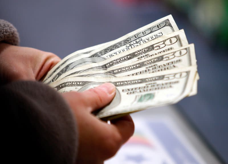 FILE PHOTO: A customer counts her money at the register of a Toys R Us store on the Thanksgiving Day holiday in Manchester