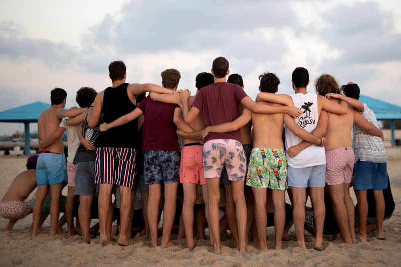 FILE PHOTO: Youths wearing bathing suits, huddle together for a picture as they visit Zikim beach, amid the coronavirus disease (COVID-19) outbreak, in southern Israel