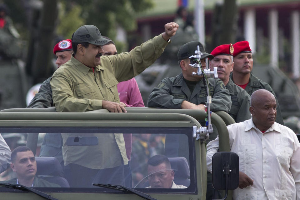 FILE - In this April 13, 2018, file photo, Defense Minister Vladimir Padrino Lopez, center right face obscured, and Gen. Ivan Hernández, standing behind Padrino Lopez, head of both the presidential guard and military counterintelligence, accompany Venezuela's President Nicolas Maduro as they arrive in Caracas, Venezuela. The Associated Press has learned that at least twice since 2016, the U.S. government missed chances to cultivate relations with three regime insiders, including Padrino and Hernández, who National Security Adviser John Bolton said backed out of a plan to topple Maduro. (AP Photo/Ariana Cubillos, File)