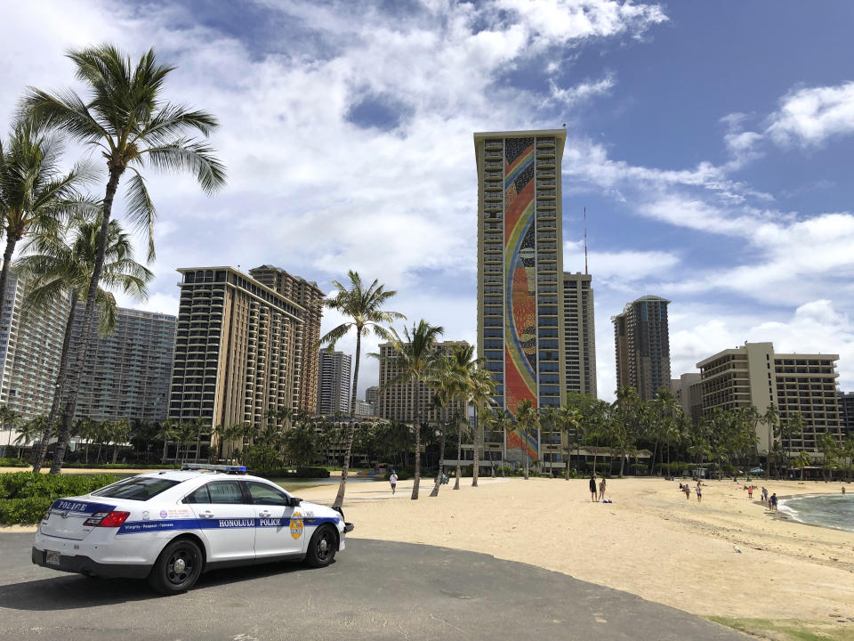 FILE - In this March 28, 2020 file photo a police officer arrives to tell people to leave Waikiki Beach in Honolulu. Former Hawaii television reporter Angela Keen knows how to track people down. During the coronavirus pandemic, she's putting her people-finding skills to use as one of the original members of a Facebook group that has grown to more than 2,000 people called "Hawaii Quarantine Kapu Breakers." Kapu is a Hawaiian word that means laws or rules. The group is focused on finding people who violate Hawaii's 14-day quarantine on travelers arriving to the state. (AP Photo/Caleb Jones,File)