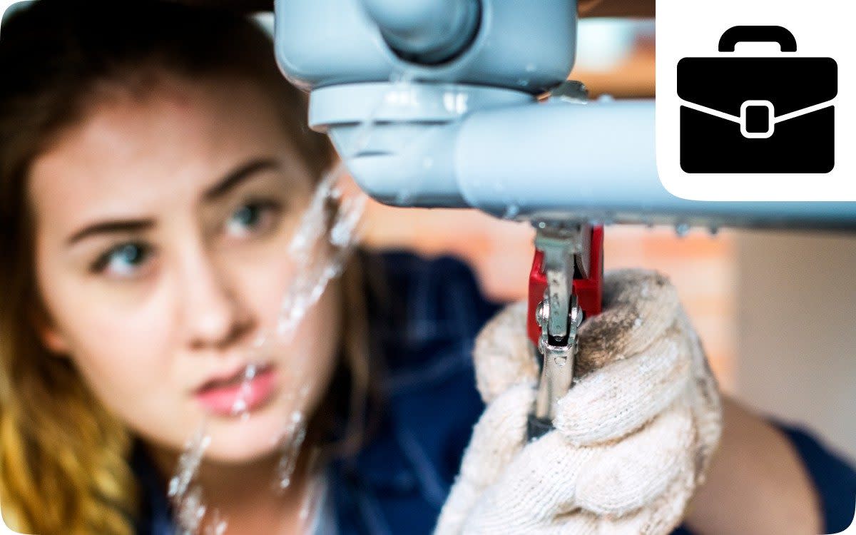 Female plumber fixing a leaking undersink pipe