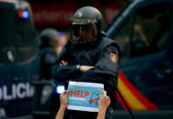 A protestor holds up a sign in front of a line of Spanish national police who surrounded the leftist CUP party headquarters in Barcelona, Spain, September 20, 2017. REUTERS/Albert Gea