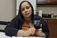 In this Wednesday, Feb. 26, 2020 photo, Yarelis Gutierrez Barrios holds up a cell phone photo at her home in Tampa, Fla., of herself with her partner Roylan Hernandez Diaz, a Cuban asylum seeker who hanged himself in a Louisiana prison. An Associated Press investigation into Hernandez’s death last October found neglect and apparent violations of government policies by jailers under U.S. Immigration and Customs Enforcement. (AP Photo/Chris O'Meara)