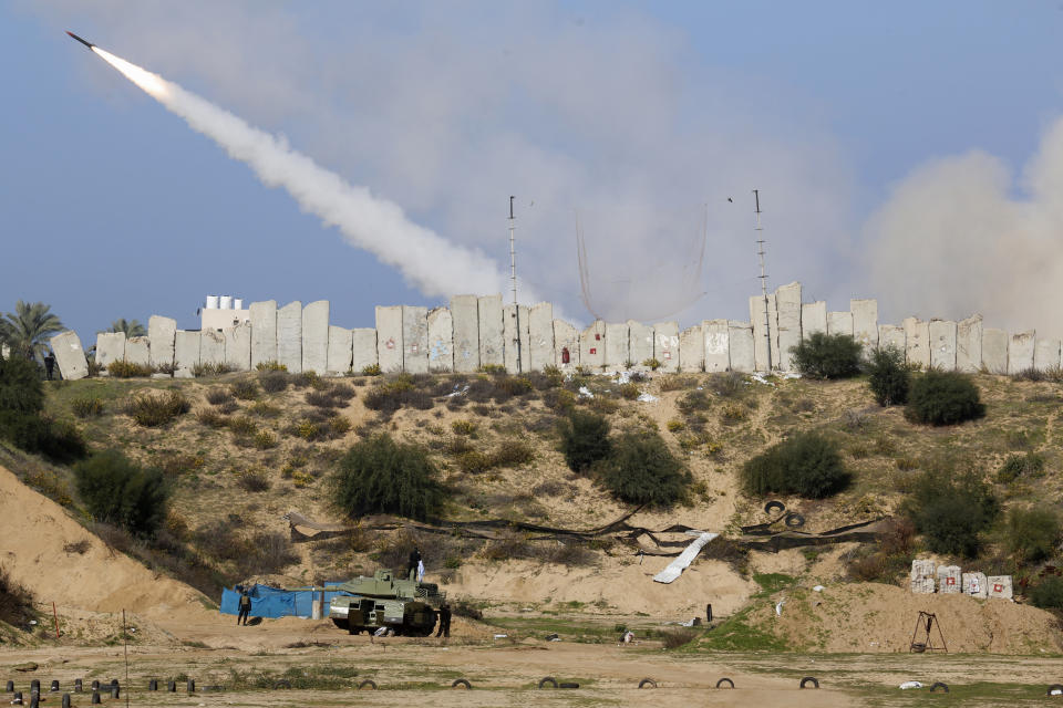 Palestinian militants stand around a replica of a tank while watching a rocket fired during a military drill organized by military factions outside Gaza City, Tuesday, Dec. 29, 2020. Palestinian militants in the Gaza Strip fired a salvo of rockets into the Mediterranean Sea on Tuesday as part of a self-styled military drill aimed at preparing for a possible war with Israel. (AP Photo/Adel Hana)