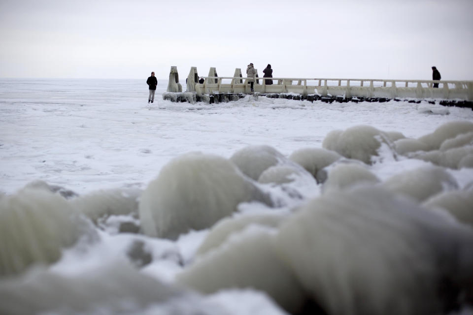 In this image taken Thursday Feb. 9, 2012, Tourists admire the frozen IJsselmeer inland sea on Afsluitdijk, a dike closing off the Wadden sea and North Sea from IJsselmeer inland sea, northern Netherlands. Rising in a thin line through the surface of waters separating the provinces of North Holland and Friesland, the 87-year-old Afsluitdijk is one of the low-lying Netherlands' key defenses against the sea. With climate change bringing more powerful storms and rising sea levels, it's getting a major makeover. (AP Photo/Peter Dejong)