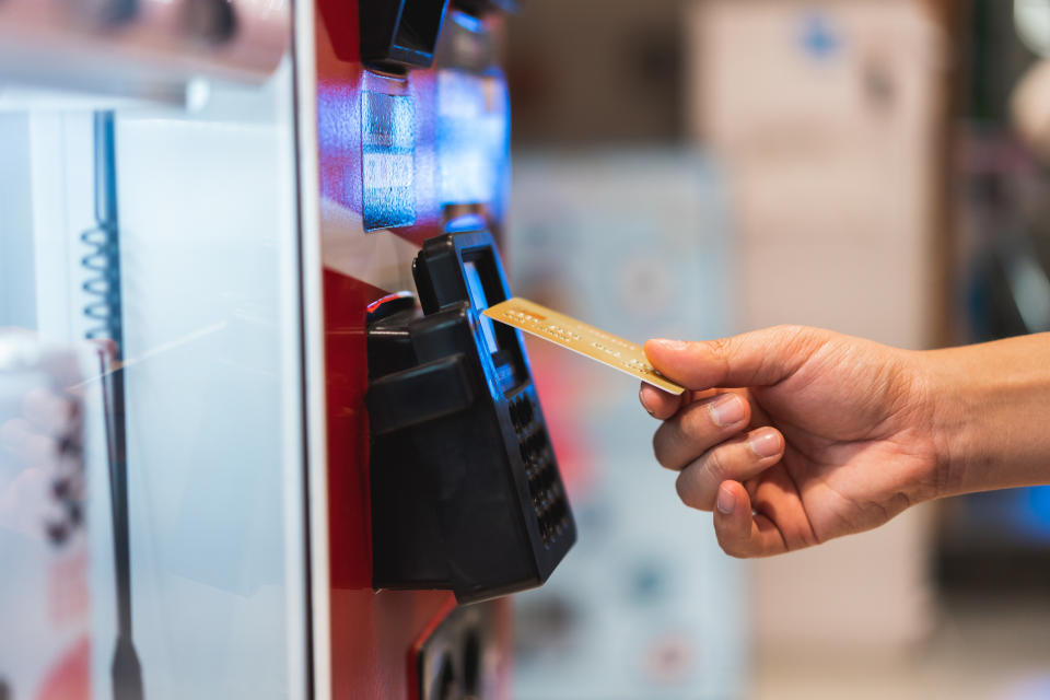 A person using a card at a vending machine payment slot