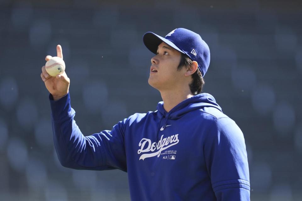 Dodgers' Shohei Ohtani gestures on the field before a baseball game against the Twins