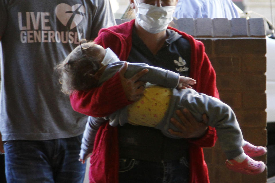 Asylum seekers wearing masks enter a door while attending a mandatory immigration court hearing on Monday, March 16, 2020, in El Paso, Texas. They are not suspected of carrying the Corona virus. Many immigration court hearings were cancelled Monday to curb spread of COVID-19. The migrants are required to live in nearby Ciudad, Juarez, Mexico, which had no confirmed cases as of Monday morning. (AP Photo/Cedar Attanasio)