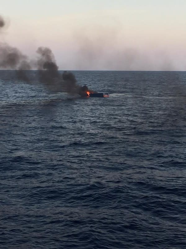 A boat burns after being set on fire by the coast guard, after they rescued migrants at the Mediterranean Sea off the coast of Libya