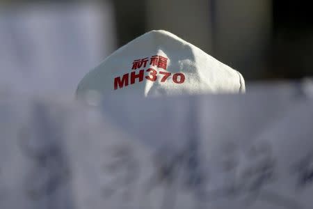 A family member of a passenger onboard Malaysia Airlines flight MH370 which went missing in 2014 holds a banner during a gathering in front of the Malaysian Embassy on the second anniversary of the disappearance of MH370, in Beijing, China, March 8, 2016. REUTERS/Damir Sagolj