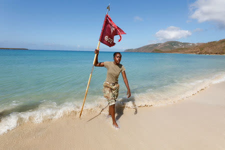 Army Specialist Cerelai Spencer of Spring Lake, North Carolina, carries the 602nd Area Support Medical Company flag out of the surf after placing it there for a company, during some down time as they await transport on a Navy landing craft during their evacuation in advance of Hurricane Maria, in Charlotte Amalie, St. Thomas, U.S. Virgin Islands September 17, 2017. REUTERS/Jonathan Drake