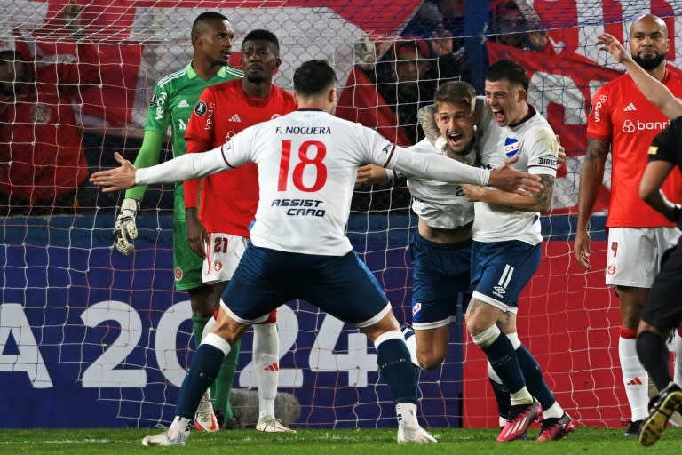 Bruno Damiani (C) comemora com Juan Ignacio Ramírez (D) e Fabián Noguera em jogo do Nacional entre Porto Alegre pela Copa Libertadores em 7 de junho de 2023 em Montevidéu (Pablo PORCIUNCULA)