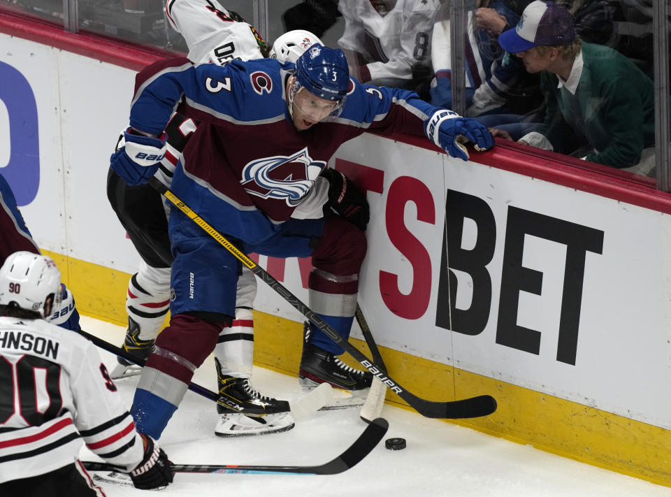 Colorado Avalanche defenseman Jack Johnson, front, fights for control of the puck with Chicago Blackhawks left wing Alex DeBrincat in the first period of an NHL hockey game Wednesday, Oct. 13, 2021, in Denver. (AP Photo/David Zalubowski)