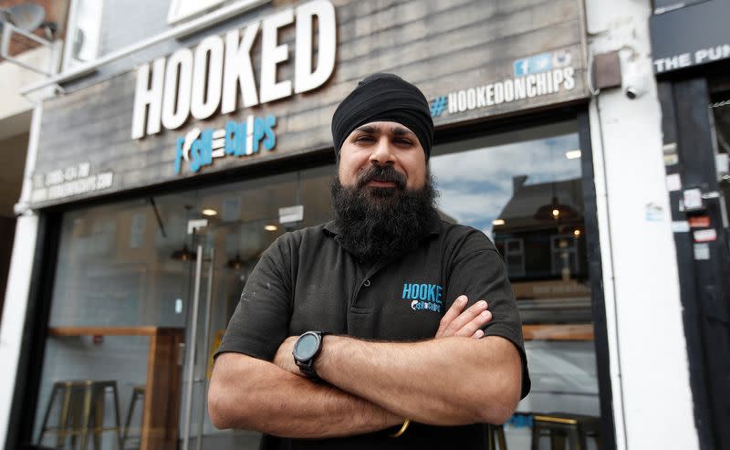 Owner of Hooked Fish and Chips shop, Bally Singh, poses for a photograph in front of his take-away in West Drayton