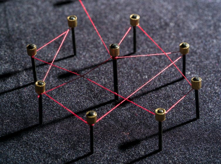 Nine pins connected be red string.