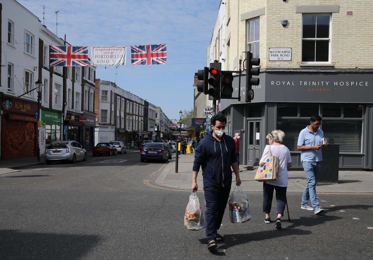 A man wearing personal protective equipment (PPE) shops in Portobello Road, west London, as the UK continues in lockdown to help curb the spread of the coronavirus. Picture date: Sunday April 26, 2020. 