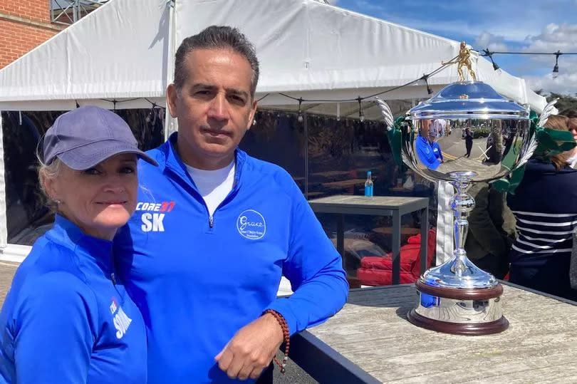Sinead O'Malley and Sanjoy Kumar pictured with The Grace O'Malley-Kumar Cup, both wearing blue tops sporting the logo of the foundation set up in their daughter's memory