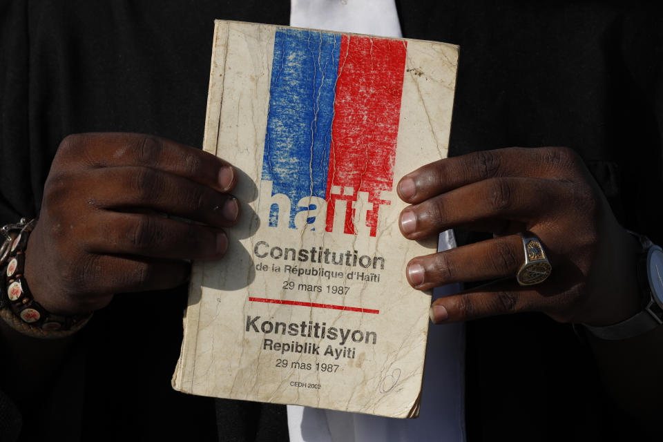 Entrepreneur and youth leader Pascéus Juvensky St. Fleur, 26, holds up his copy of the Haitian constitution during an interview with the AP, in Port-au-Prince, Haiti, Tuesday, Oct. 8, 2019. St. Fleur says the protests are not only about replacing a president, but changing a system. "It's not one person, it's not one regime, it's not a president, it's not the opposition, it's not the bourgeoisie, but it's us who should do it," he said. "We dream of, and we want, a better Haiti."(AP Photo/Rebecca Blackwell)