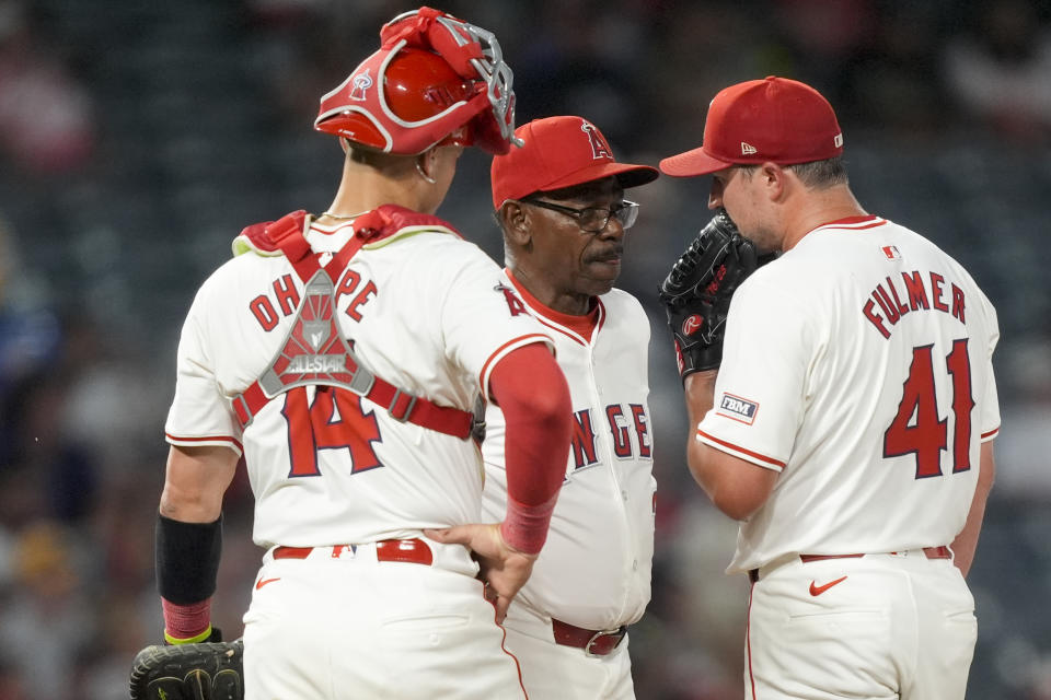 Los Angeles Angels manager Ron Washington, center, speaks with pitcher Carson Fulmer, right, and catcher Logan O'Hoppe during the seventh inning of a baseball game against the Texas Rangers, Monday, July 8, 2024, in Anaheim, Calif. (AP Photo/Ryan Sun)