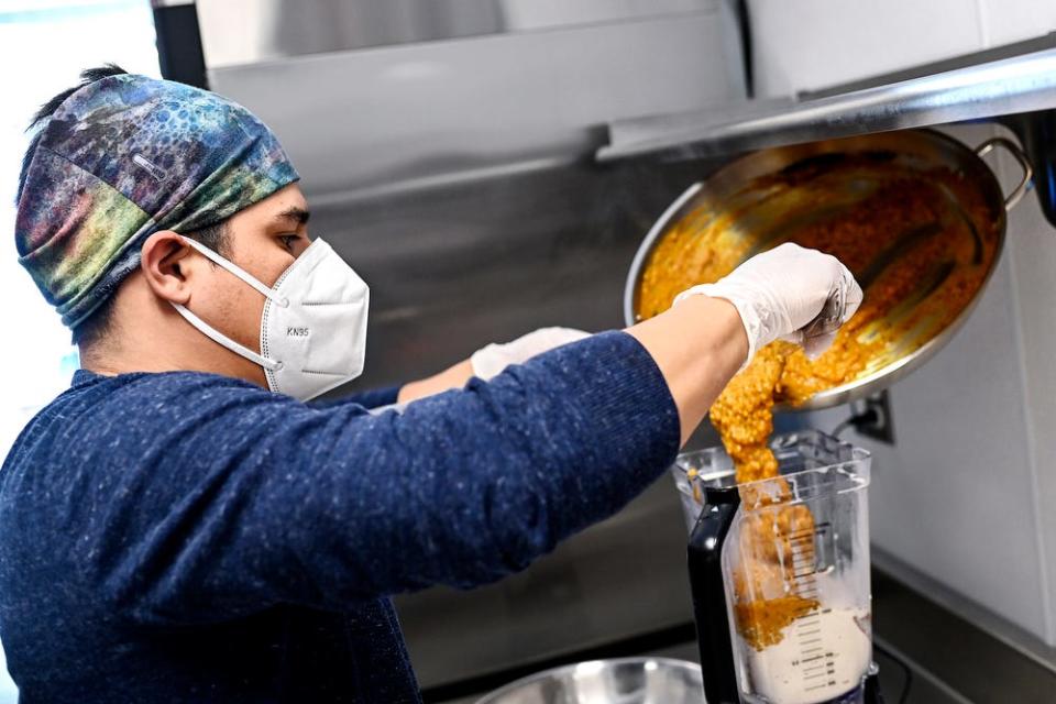 Jose Aste, owner of Tantay, mixes a sauce for a Peruvian chicken stew on Wednesday, March 10, 2021, in the accelerator kitchen at the Allen Neighborhood Center in Lansing.