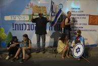 Israeli protesters hold signs during a demonstration against Israeli Prime Minister Benjamin Netanyahu outside his official residence in Jerusalem, Saturday, June 12, 2021. If all goes according to plan, Israel will swear in a new government on Sunday, ending Prime Minister Benjamin Netanyahu's record 12-year rule and a political crisis that inflicted four elections on the country in less than two years. (AP Photo/Ariel Schalit)