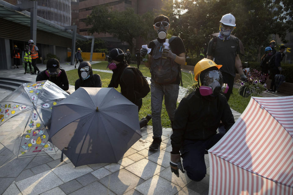 A protestor carrying molotov cocktails stands with others holding umbrellas as they wait for a possible volley of tear gas at the Hong Kong Polytechnic University campus in Hong Kong, Thursday, Nov. 14, 2019. University students from mainland China and Taiwan are fleeing Hong Kong, while those from three Scandinavian countries have been moved or urged to leave as college campuses become the latest battleground in the city's 5-month-long anti-government unrest. (AP Photo/Ng Han Guan)