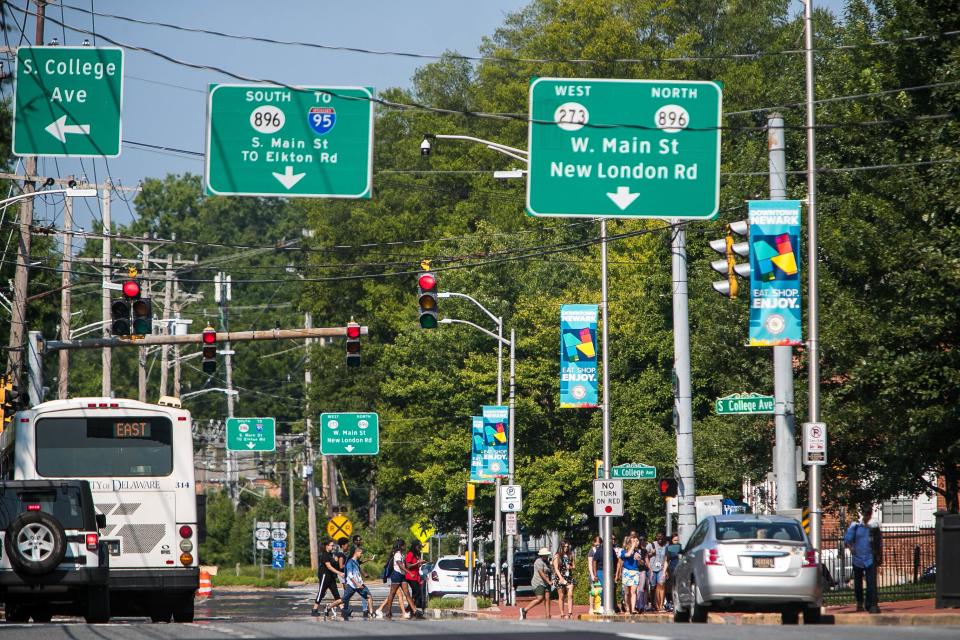 Students use a crosswalk at a traffic light on Main Street in Newark.