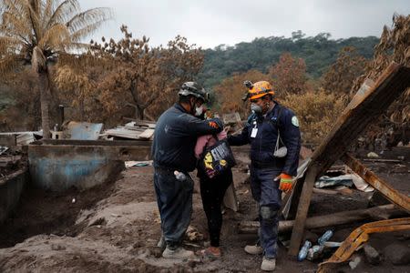 Eufemia Garcia, 48, who lost 50 members of her family during the eruption of the Fuego volcano, is embraced by a rescue worker as she searches for her family in San Miguel Los Lotes in Escuintla, Guatemala, June 15, 2018. REUTERS/Carlos Jasso
